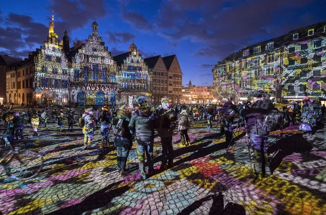 Picture taken on March 20, 2018 shows visitors standing at the Roemer square in Frankfurt am Main, western Germany, and watching the light installation “Frankfurt Fades” by artist Philipp Geist presented during the Luminale Festival of Light. The festival will be running until March 23, 2018. (Photo by Boris Roessler/AFP Photo/DPA)