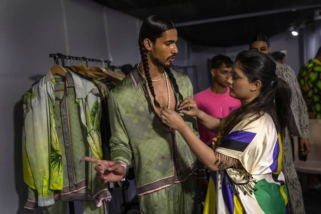 A designer checks an outfit on a model backstage during Lakme Fashion Week X FDCI in Mumbai, India, Thursday, March. 9, 2023. (Photo by Rafiq Maqbool/AP Photo)