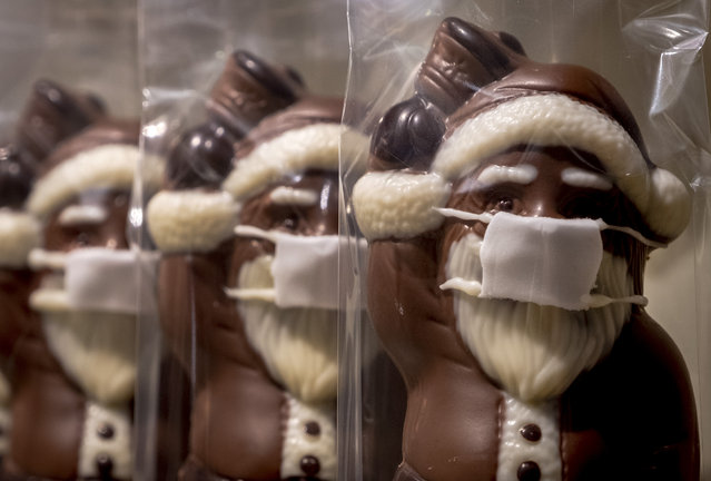 A confectioner offers chocolate Santa Claus wearing a face mask, displayed in the window of a shop in central Frankfurt, Germany, Sunday, November 22, 2020. (Photo by Michael Probst/AP Photo)