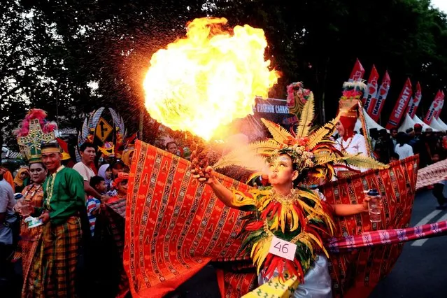 A girl wearing a silk weaving costume spits fire during a Fashion Carnival in Makassar, Indonesia South Sulawesi province, October 16, 2016. (Photo by Sahrul Manda Tikupadang/Reuters/Antara Foto)