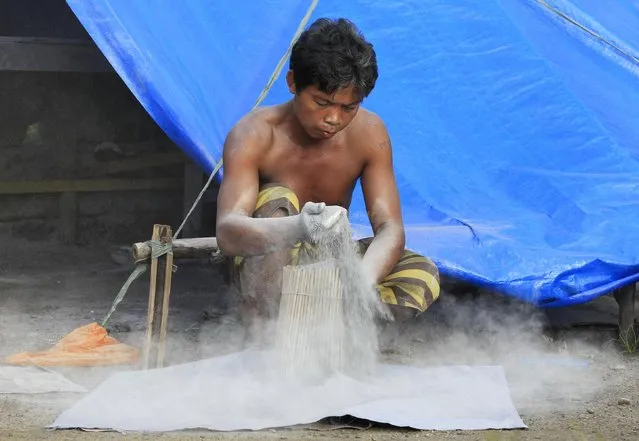 A worker puts firecracker powder in sparklers outside a makeshift firecracker factory in Bocaue town, Bulacan province, north of Manila December 27, 2014. (Photo by Romeo Ranoco/Reuters)