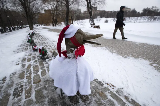 A man passes a sculpture “Make Way for Ducklings” dressed in Christmas costumes in Moscow's Novodevichy Park, Russia, Friday, December 25, 2020. The copy of sculpture by Nancy Schon installed in the Boston Public Garden, U.S., became dressed in Santa Claus' hat every Catholic Christmas for several years like a tradition. Orthodox Christians celebrate Christmas on Jan. 7, in accordance with the Julian calendar. (Photo by Pavel Golovkin/AP Photo)
