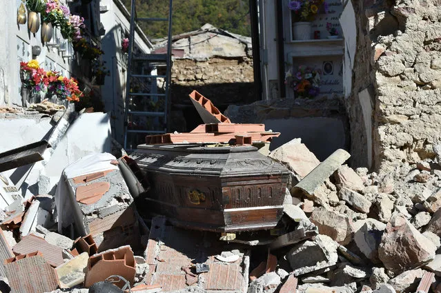 A coffin is seen in the rubbles of the collapsed cemetery of Campi near Norcia, on October 31, 2016, a day after a 6.6 magnitude earthquake hit central Italy. It came four days after quakes of 5.5 and 6.1 magnitude hit the same area and nine weeks after nearly 300 people died in an August 24 quake that devastated the tourist town of Amatrice at the peak of the holiday season. Italy's most powerful earthquake in 36 years dealt a new blow Sunday to the country's seismically vulnerable heart, sending terrified residents fleeing for the third time in nine weeks and flattening a revered six-century-old church. (Photo by Alberto Pizzoli/AFP Photo)
