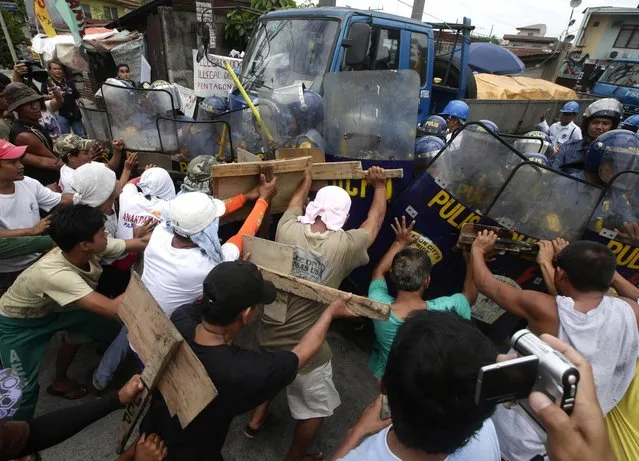 Striking workers of a steel factory clash with police and company guards to prevent the company from taking out their products Thursday June 20, 2013 at suburban Quezon city north of Manila, Philippines. The workers went on strike for more than a month now following the decision of the company to downsize its working force allegedly for economic reasons which the workers branded as illegal dismissal. (Photo by Bullit Marquez/AP Photo)