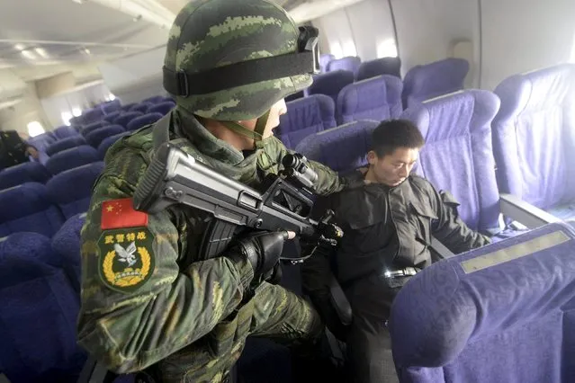 An armed paramilitary policeman checks a mock hijacker during an anti-terrorism drill on plane hijacking, on a passenger jet at the Beijing Capital International Airport, in Beijing, China, December 3, 2015. (Photo by Reuters/Stringer)