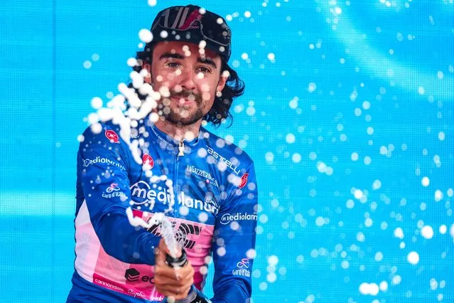 EF Education-EasyPost's Irish rider Ben Healy sprays sparkling wine as he celebrates his best climber's blue jersey on the podium after the seventeenth stage of the Giro d'Italia 2023 cycling race, 197 km between Pergine Valsugana and Caorle, near Venice on May 24, 2023. (Photo by Luca Bettini/AFP Photo)