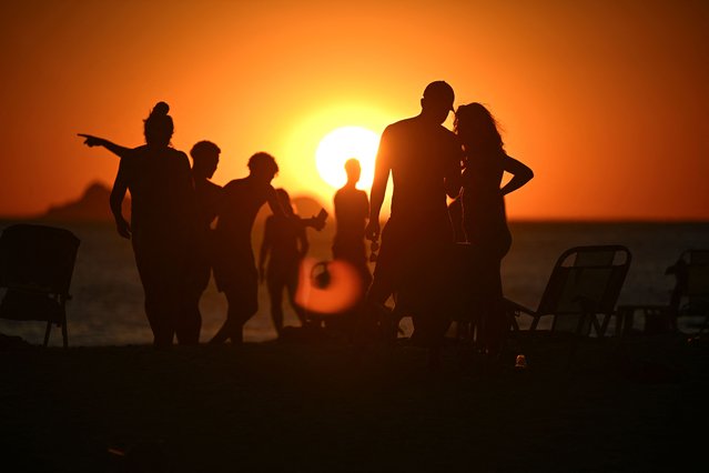 People observe the sunset at Ipanema beach in Rio de Janeiro, Brazil on December 10, 2025. (Photo by Mauro Pimentel/AFP Photo)