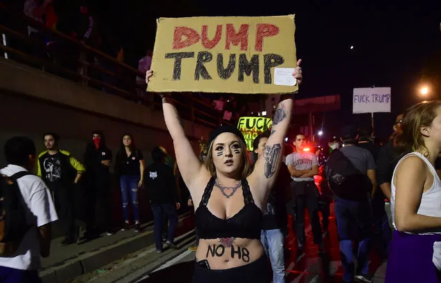 Protesters on a freeway onramp amid a chaotic traffic situation with the shutdown of the freeway in downtown Los Angeles, California after midnight early on November 10, 2016 as protesters angry over Donald J. Trump's election as the next US president marched in downtown Los Angeles through the evening and shut down portions of the Hollywood (101) Freeway. Thousands of protesters rallied across the United States expressing shock and anger over Donald Trump's election, vowing to oppose divisive views they say helped the Republican billionaire win the presidency. (Photo by Frederic J. Brown/AFP Photo)