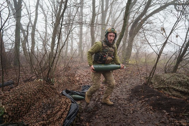 A Ukrainian serviceman of the Da Vinci Wolves Battalion carries an artillery shell before firing toward Russian positions at the front line in eastern Ukraine, on Friday, Nov. 28, 2025. (Photo by A Ukrainian serviceman of the Da Vinci Wolves Battalion carries an artillery shell before firing toward Russian positions at the front line in eastern Ukraine, on Friday, November 28, 2025. (Photo by Evgeniy Maloletka/AP Photo)