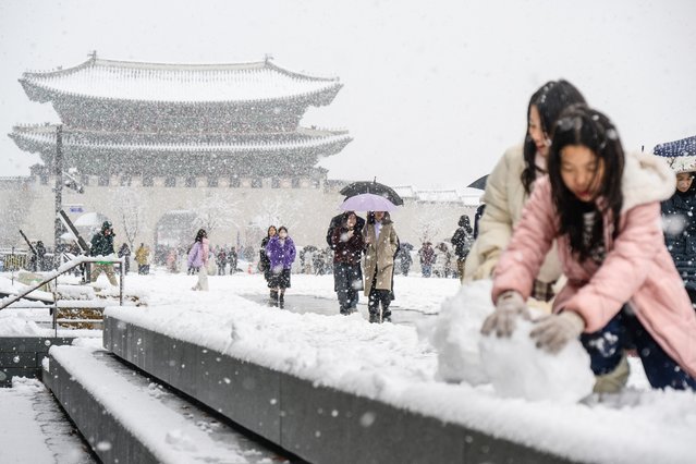 Pedestrians walk in front of the Gyeongbokgung Palace amid heavy snowfall in central Seoul on November 27, 2024. South Korea's capital was blanketed on November 27 by the heaviest November snowfall since records began over a century ago, the weather agency said. (Photo by Anthony Wallace/AFP Photo)