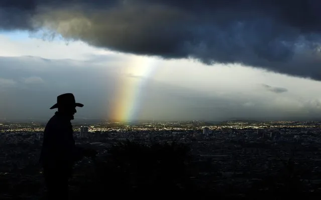 A man walks as a rainbow is seen below dark clouds in San Jose city January 29, 2015. (Photo by Juan Carlos Ulate/Reuters)