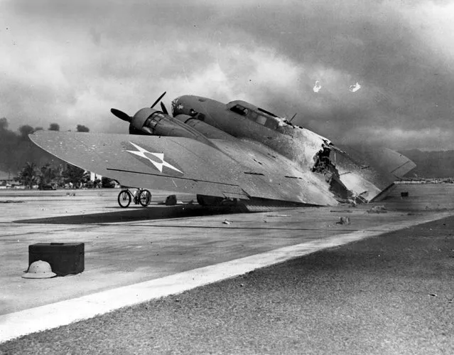A wrecked U.S. Army Air Corps B-17C bomber lies at Hickam Air Field, following the end of the Japanese raid on Pearl Harbor, Hawaii, U.S. December 7, 1941. This plane, piloted by Captain Raymond T. Swenson, was one of those that arrived during the raid after flying in from California. It was hit by a strafing attack after landing and burned in half. (Photo by Reuters/U.S. Navy/National Archives)