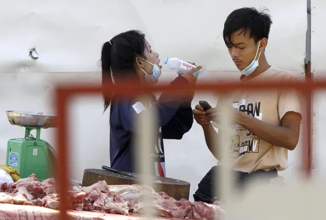 A couple of local vendors waits for customers as they sell pork meats at a motor-cart's mobile market in Phnom Penh, Cambodia, Sunday, April 25, 2021. The country's capital Phnom Penh has been locked down for two weeks from April 15, following a sharp rise in COVID-19 cases. (Photo by Heng Sinith/AP Photo)