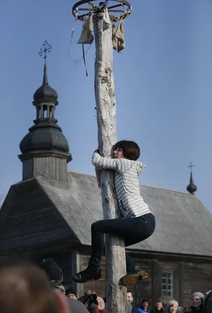 A woman climbs a pole during Maslenitsa celebrations, or Shrovetide, in the village of Ozertso, in outskirts of Minsk, Belarus, Sunday, February 22, 2015. Maslenitsa is a traditional Russian and Belarusian holiday marking the end of winter that dates back to pagan times. (Photo by Sergei Grits/AP Photo)