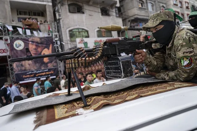A Hamas militant holds a squad automatic weapon perched atop a truck during a parade through the streets for Bassem Issa, a top Hamas' commander, who was killed by Israeli Defense Force military actions prior to a cease-fire reached after an 11-day war between Gaza's Hamas rulers and Israel, in Gaza City, Saturday, May 22, 2021. (Photo by John Minchillo/AP Photo)