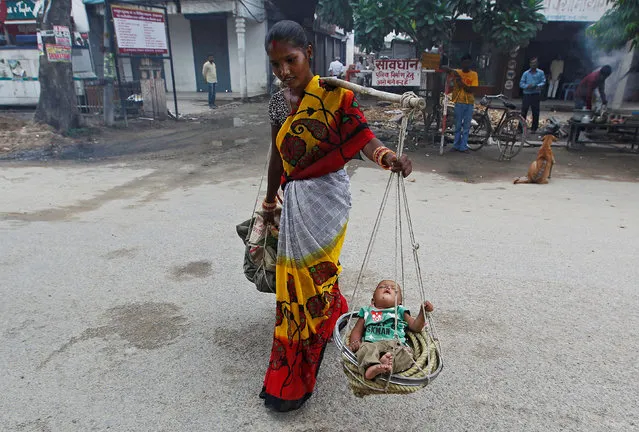 A woman carries her child in a basket as she walks on a road in Allahabad, India, August 11, 2016. (Photo by Jitendra Prakash/Reuters)