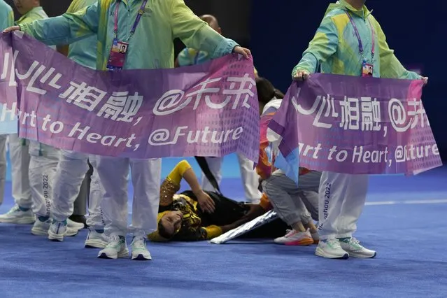 Volunteers hold up banners with the slogan “Heart to Heart” to block the view as medics attend to Iran's Mina Panahi Dorcheh who injured her leg in the Wushu Women's Nanquan competition for the 19th Asian Games in Hangzhou, China, Tuesday, September 26, 2023. Regional outward aggression has taken a backseat to unctuous charm as China sought to win the hearts of more than 40 Asian nations and regions by dazzling them with technology and slathering them with praise. (Photo by Ng Han Guan/AP Photo)