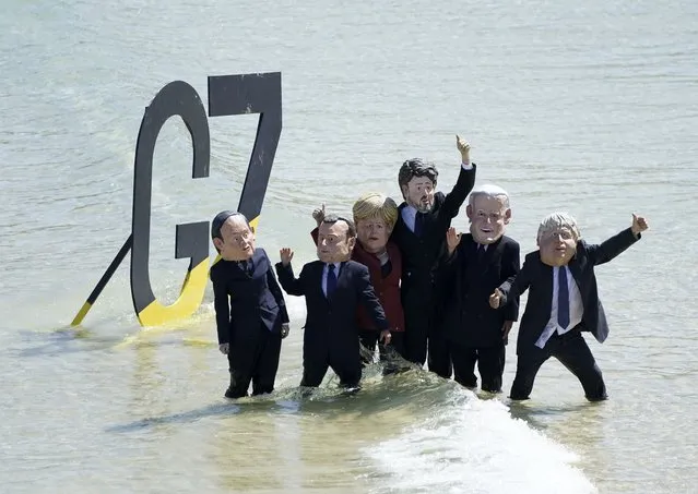 Protestors wearing giant heads portraying G7 leaders pose after a demonstration on a beach outside the G7 meeting in St. Ives, Cornwall, England, Sunday, June 13, 2021. Leaders of the G7 wrap up three days of meetings in Carbis Bay Sunday, in which they discussed such topics as COVID-19, climate, foreign policy and the economy. Leaders portrayed from left, Japan's Prime Minister Yoshihide Suga, French President Emmanuel Macron, German Chancellor Angela Merkel, Canadian Prime Minister Justin Trudeau, U.S. President Joe Biden and British Prime Minister Boris Johnson. (Photo by Jon Super/AP Photo)