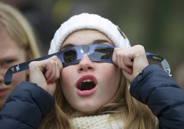 A girl looks up to try to view a partial solar eclipse outside the Planetarium of the Royal Observatory of Belgium in Brussels March 20, 2015. The total eclipse is visible in parts of the north Atlantic and Scandinavia, and with a 80-85 percent partial eclipse across Belgium. (Photo by Yves Herman/Reuters)