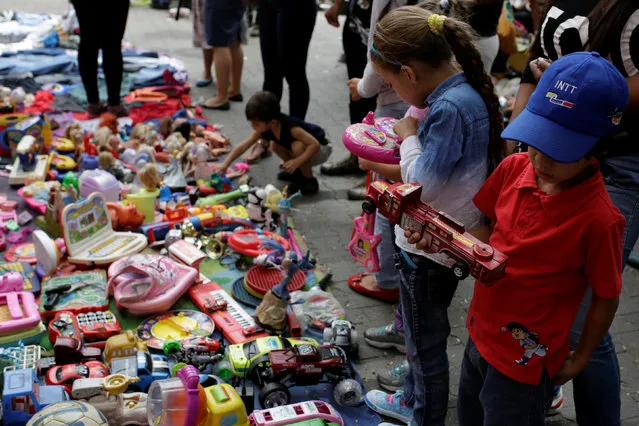 Children look at second-hand toys at a street market in the slum of Catia in Caracas, Venezuela December 21, 2016. (Photo by Marco Bello/Reuters)