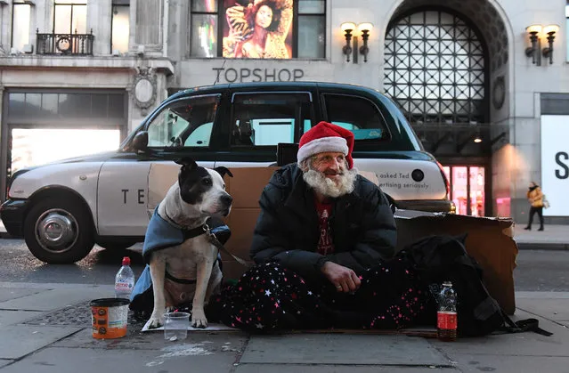 Francis, 56, from southwest Scotland with his Staffordshire Bull Terrier, Milo, sits on Oxford Street in London, Britain, 20 December 2018. Francis has been on the streets of London for eight years after losing his son and breaking up with his partner. “sh*t happens in life” Francis says. “I'll be right here for Christmas”. London now accounts for a quarter of Britain's homeless. Some twenty five thousand people across the UK are facing Christmas on the street. (Photo by  Andy Rain/EPA/EFE)