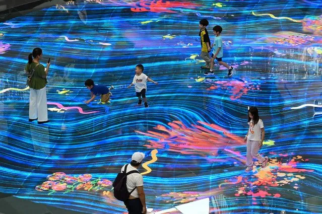 Children play with an interactive projection on the floor at the Marina Bay Sands mall in Singapore on October 27, 2023. (Photo by Roslan Rahman/AFP Photo)