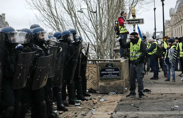 Demonstrators wearing yellow vests face riot police officers during a protest in Paris, Saturday, January 5, 2019. Hundreds of protesters were trying to breathe new life into France's apparently waning yellow vest movement with marches in Paris and gatherings in other cities. (Photo by Kamil Zihnioglu/AP Photo)