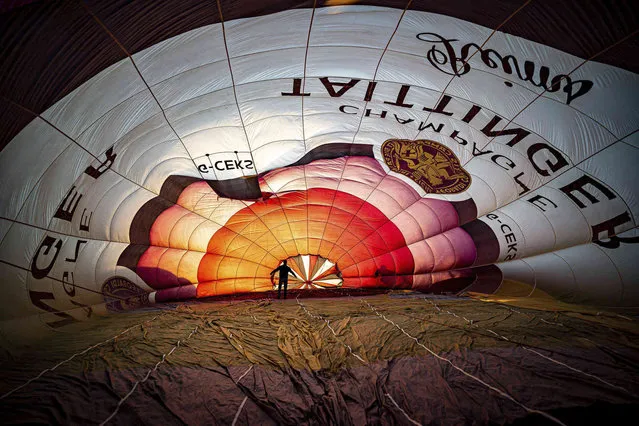 Balloon pilots check the rigging inside a balloon canopy as they prepare for the first mass ascent during “Fiesta Fortnight” in Filton, England, Wednesday August 4, 2021. The Bristol International Balloon Fiesta will see some hundreds of balloons floating in the skies of southwest England over the two-week festival. (Photo by Ben Birchall/PA Wire via AP Photo)