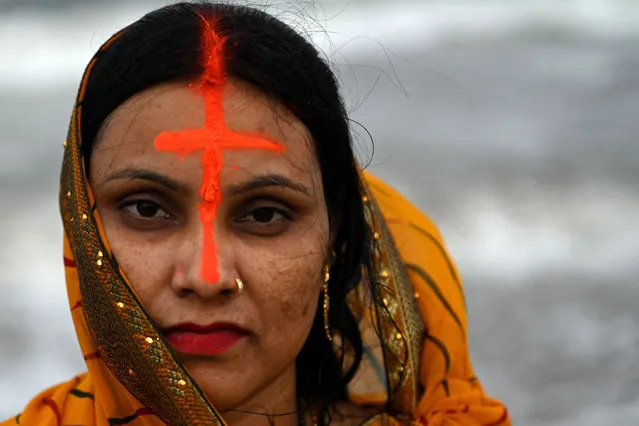 A devotee looks while offering prayers to Sun God at Marina beach on the occasion of the Hindu festival of “Chhath Puja” in Chennai, India on October 30, 2022. (Photo by Arun Sankar/AFP Photo)