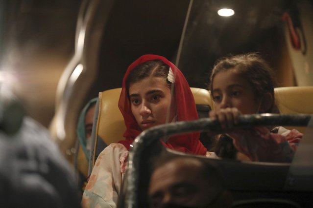Afghan evacuees from Afghanistan sit in a bus after the arrival of the second flight with 95 passengers at the International Airport in Tirana, Albania, Friday, August 27, 2021. Albania on Friday housed its first group of Afghan evacuees who made it out of their country despite days of chaos near the Kabul airport, including an attack claimed by the Islamic State group. (Photo by Franc Zhurda/AP Photo)