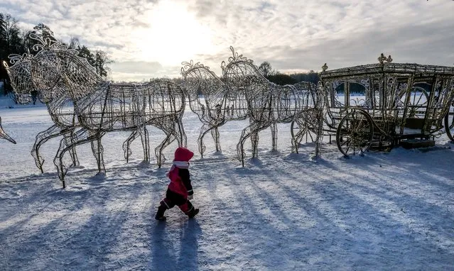 A boy walks past a Christmas decoration of a carriage in Tsaritsyno park in Moscow, Russia on January 13, 2019. (Photo by Yuri Kadobnov/AFP Photo)