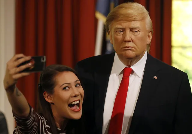 Madame Tussauds' employee Helen Smith taks a selfie next to the wax figure of US President-elect Donald Trump, as they unveil the figure just days ahead of the American's Presidential Inauguration in Washington in London, Wednesday, January 18, 2017. The figure will now reside in Madame Tussauds' London Oval Office alongside fellow famous politicians and global icons also immortalised in wax. (Photo by Frank Augstein/AP Photo)