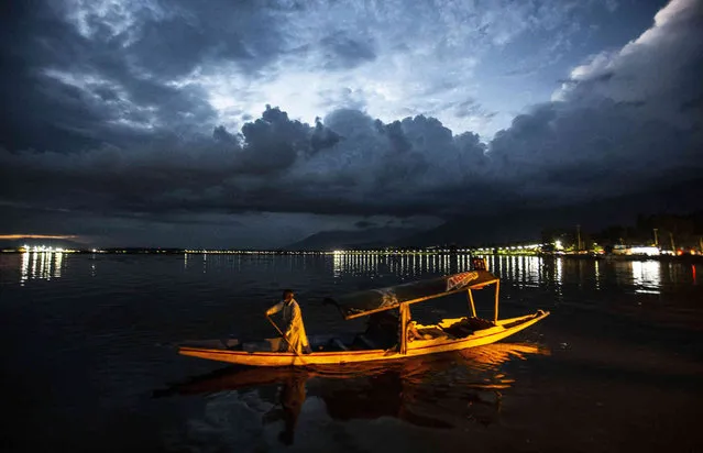 A Kashmiri boatman returns at the shore of the Dal lake after day's work, in Srinagar, Indian controlled Kashmir, Sunday, August 1, 2021. (Photo by Mukhtar Khan/AP Photo)