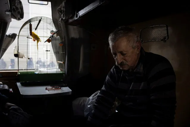 Aleksandr Batrak sits with his pet bird in an evacuation train in Pokrovsk, Ukraine on February 20, 2024. (Photo by Thomas Peter/Reuters)