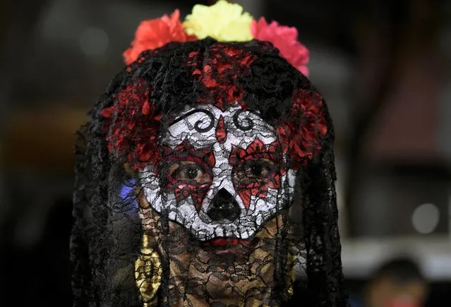 A transgender person looks on near offerings for victims of hate crimes on an alter, as part of Day of the Dead ceremonies, by civil organisations for the human rights of transgender people in Mexico City on November 2, 2021. (Photo by Alfredo Estrella/AFP Photo)