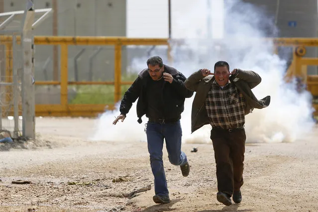 Palestinians run from tear gas fired by Israeli troops during a protest marking the 40th Land Day anniversary, outside Ofer military prison near the West Bank city of Ramallah, Wednesday, March 30, 2016. Land Day commemorates riots on March 30, 1976, when many were killed during a protest by Israeli Arabs whose property was annexed in northern Israel to expand Jewish communities. (Photo by Majdi Mohammed/AP Photo)
