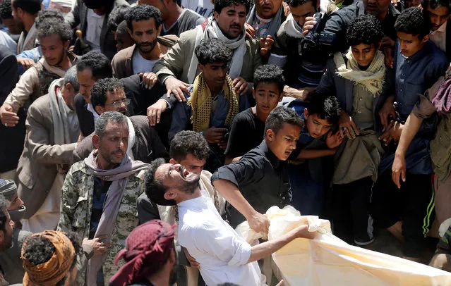 A man reacts as he lowers the body of his daughter to a grave during the burial of people who were killed by a blast in Sanaa, Yemen on April 10, 2019. (Photo by Khaled Abdullah/Reuters)