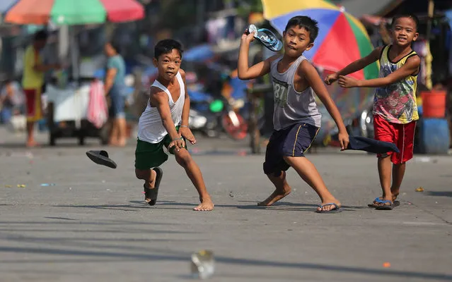 Filipino boys throw their slippers towards an empty tin can as they play a traditional Filipino game, called “Tumbang Preso”, in Navotas, north of Manila, Philippines, Wednesday, March 16, 2016. (Photo by Aaron Favila/AP Photo)