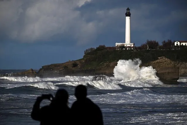 People watch waves in front of a lighthouse near the central beach, in Biarritz, southwestern France, on February 11, 2024. In the Basque Country, with its 35 kilometres of sandy and rocky coastline, more than 500 individual and collective dwellings and around 40 businesses are threatened within 20 years by rising sea levels and their consequences, according to the “Communaute d'agglomeration”. (Photo by Philippe Lopez/AFP Photo)