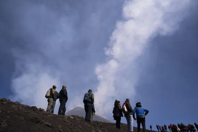 People look at volcanic vortex rings emerging from a new pit crater on the north side of the southeast crater of the Etna Volcano in Sicily, Italy, Friday, April 5, 2024. (Photo by Giuseppe Di Stefano/AP Photo)