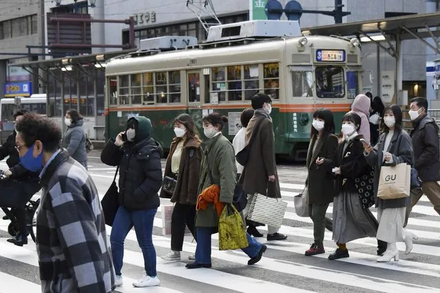 People wearing face masks cross a street in Hiroshima, western Japan Thursday, January 6, 2022. Japan approved new restrictions on Friday to curb a sharp rise in coronavirus cases in the three most affected southwestern regions of Okinawa, Yamaguchi and Hiroshima. (Photo by Kyodo News via AP Photo)