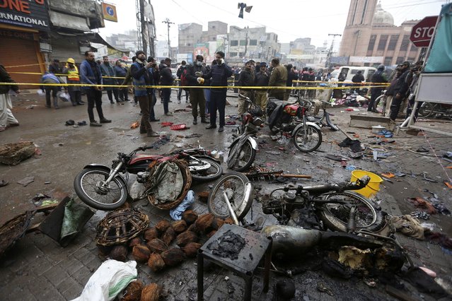 Police officials examine the site of bomb explosion, in Lahore, Pakistan, Thursday, January 20, 2022. Police said the powerful bomb exploded in a crowded bazar in Pakistan's second largest city of Lahore, killing several people and wounding dozens of others. (Photo by K.M. Chaudary/AP Photo)