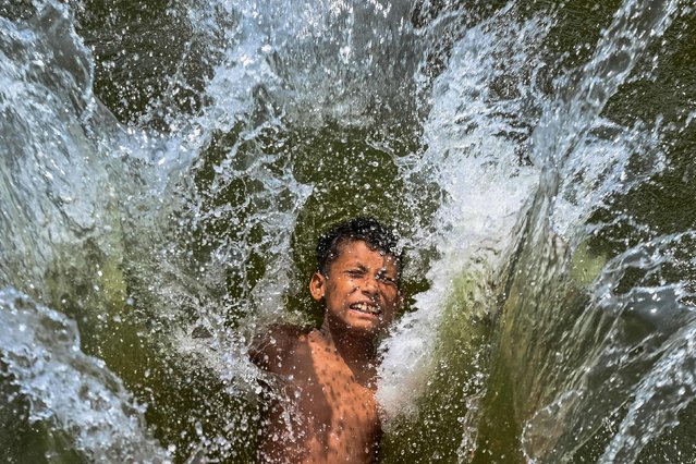 A child playfully takes a dip in a lake to get respite from the heat on a summer afternoon in Dhaka on April 29, 2024. (Photo by Munir Uz Zaman/AFP Photo)