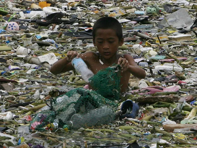 A boy collects plastic materials as he wades in murky waters while surrounded by garbage brought by Tropical Storm Saola, locally named Gener, along a Manila bay July 30, 2012. The Department of Education (DepEd) and local officials announced the suspension of classes in most parts of Metro Manila and some nearby areas on Monday due to heavy rains caused by the storm and the southwest monsoon. The Philippine Atmospheric Geophysical and Astronomical Services Administration said the storm is headed for Taiwan, but warned of rainy weather from the southwest monsoon, local media reported. (Photo by Romeo Ranoco/Reuters)