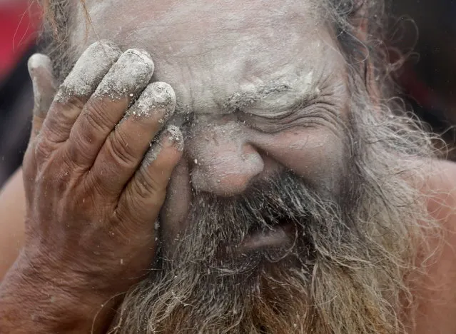 An Indian monk applies mud dust on face after taking a holy dip at Sagar Island during second day of annual fair amid Covid crisis, 130km south of Kolkata, Eastern India, 14 January 2022. (Photo by Piyal Adhikary/EPA/EFE)