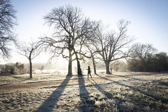 A jogger runs through a frost-covered landscape in Wanstead Park, in north east London, Thursday, January 6, 2022, after a night of low temperatures in the capital. (Photo by Stefan Rousseau/PA Wire via AP Photo)