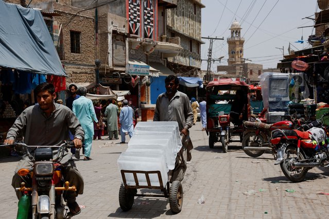 A man transports ice blocks in a trolly to supply nearby cafes during a hot summer day along a market in Jacobabad, Pakistan on May 24, 2024. (Photo by Akhtar Soomro/Reuters)
