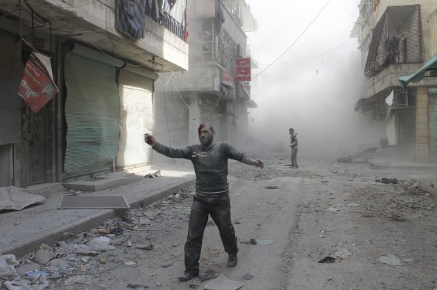 An injured man walks along a street after what activists said was a barrel bomb dropped by forces loyal to Syria's President Bashar al-Assad in Aleppo's al-Myassar neighbourhood April 16, 2014. (Photo by Firas Badawi/Reuters)
