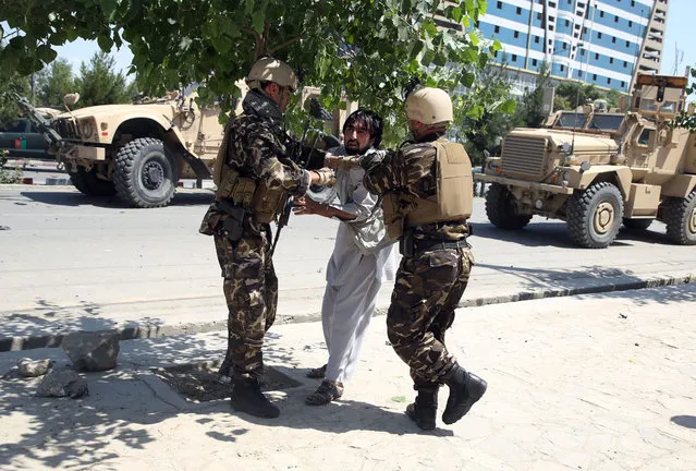 Afghan security forces beat a man at the site of a suicide car bomb attack on a NATO convoy in Kabul, Afghanistan, Tuesday, June 30, 2015. An eyewitness said the man was later released. (Photo by Massoud Hossaini/AP Photo)
