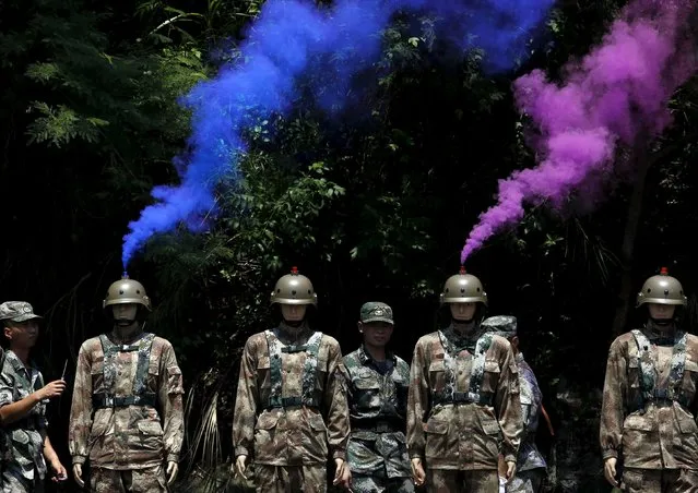 Smoke comes out from the helmets of dummies beside People's Liberation Army (PLA) soldiers during a mock shooting practice, at a PLA naval base in Hong Kong, China July 1, 2015. (Photo by Bobby Yip/Reuters)